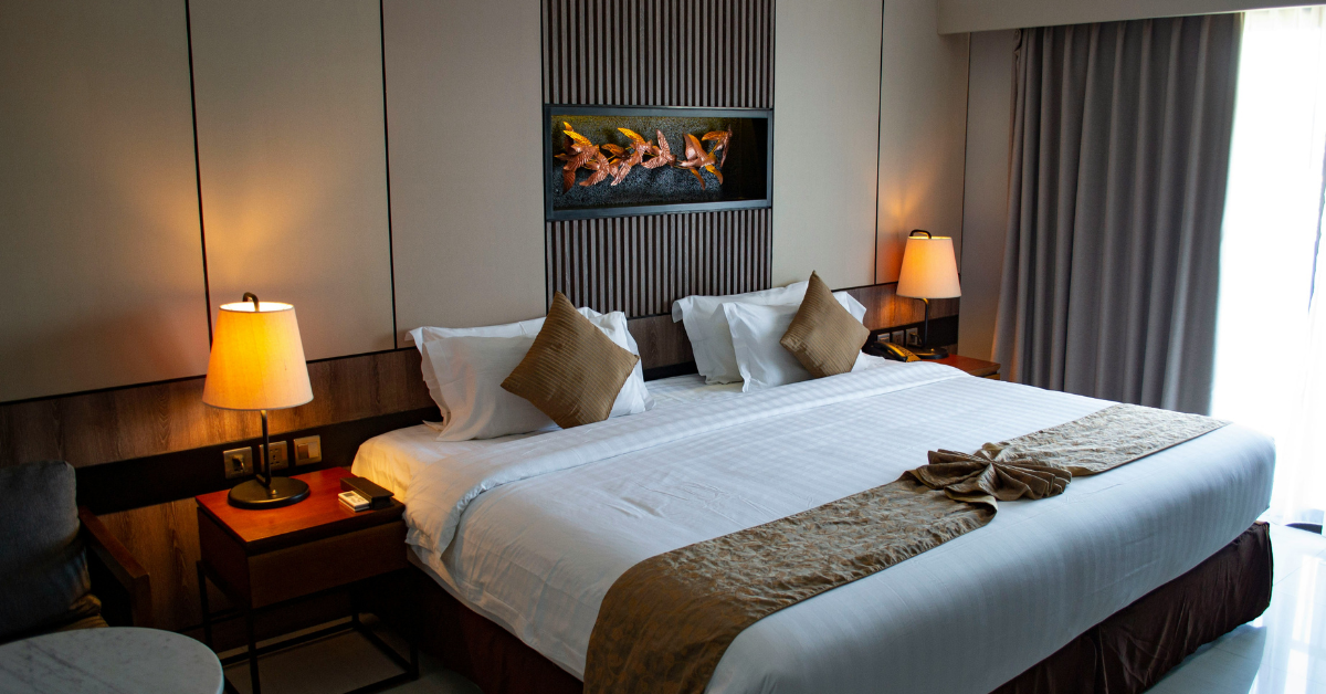 A comfortable military lodging hotel room with neutral bedding, a king size bed, and soft lighting.
