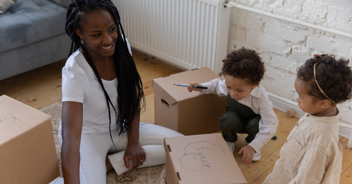 A mom and her two young children packing moving boxes for a deferred dependent PCS in the military.