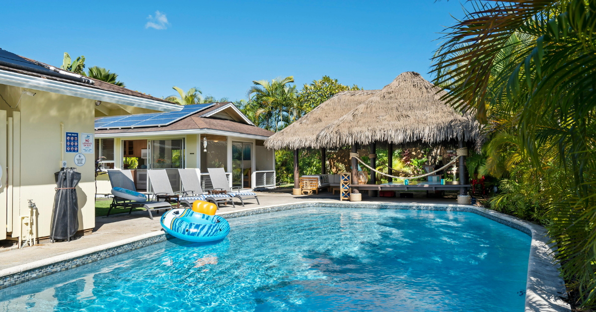 A vacation rental with a pool and lounge chairs, a thatched tiki hut, and a screened porch—perfect for military families using TLE during a PCS move.