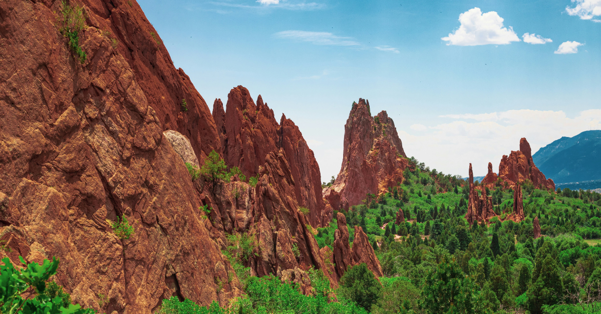 Red sandstone rocks with blue skies and trees in the foreground at Garden of the Gods in Colorado Springs, near Fort Carson.